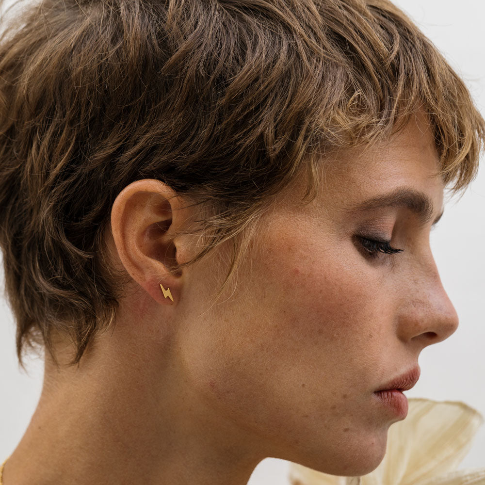 kobieta z krótkimi rudymi włosami w kolczykach z frędzlami na uszach