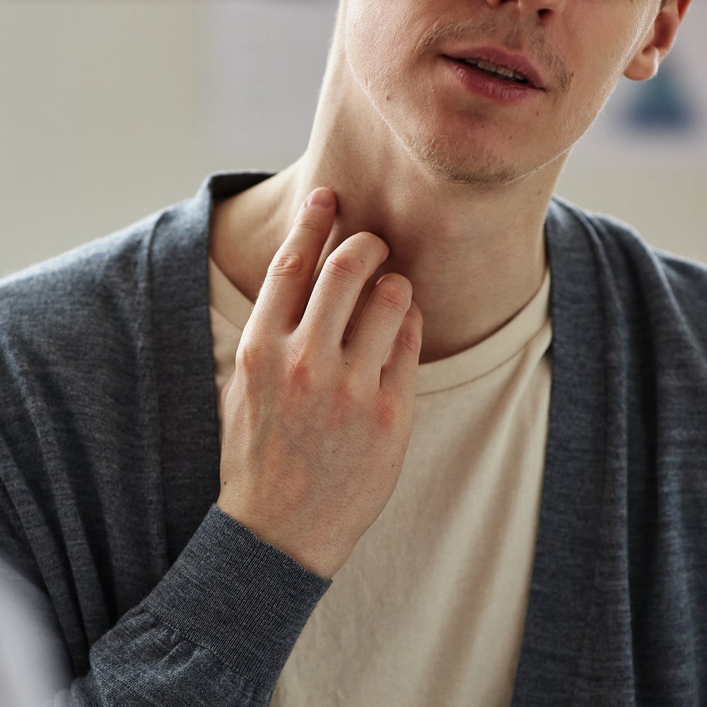 kobieta smarująca balsamem szyję po zdjęciu drapiącego wełnianego swetra