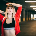 woman in black sports bra and red jacket posing in parking lot